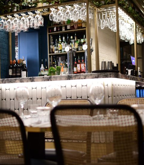 Cosy restaurant bar interior with wine glasses and bottles, warm lighting, stylish decor, relaxing atmosphere, evening dining