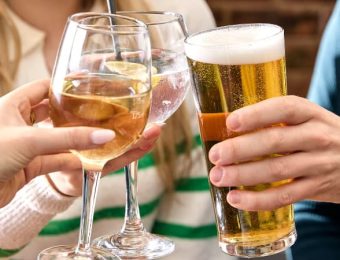 People toasting with various drinks, including beer and wine, while celebrating together in a casual setting