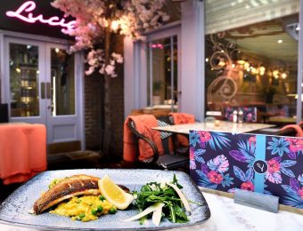Plated seafood dish with lemon and greens at an elegant restaurant setting featuring floral decor and cosy seating