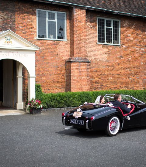Classic wedding car outside Merchant Taylors' Hall, newlyweds drive off in a black vintage convertible