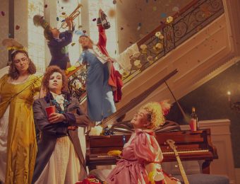People in vibrant historical costumes celebrating joyfully on a staircase with confetti and musical instruments