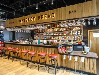 Trendy whiskey bar interior with wooden decor, red stools, and an extensive selection of spirits behind the counter