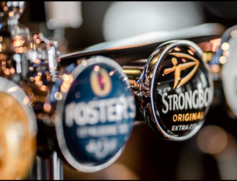 Close-up of beer taps in a pub featuring brands like Foster's and Strongbow, highlighting a classic pub atmosphere