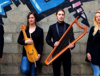 Group of musicians with traditional string instruments against graffiti wall, wearing black jackets and blue jeans