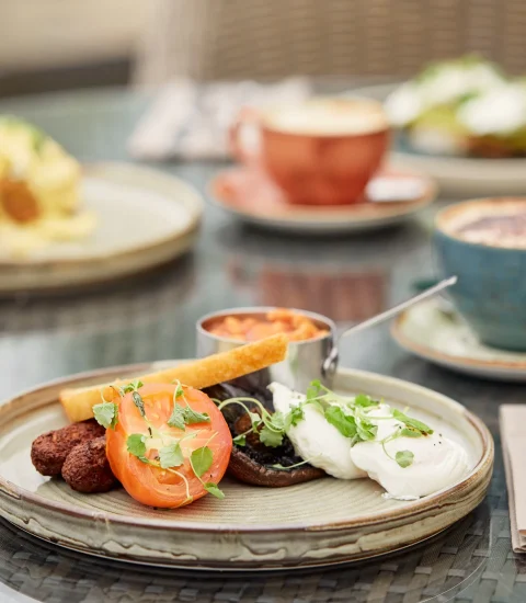 Gourmet breakfast with poached eggs, grilled tomato, toast, and coffee on a stylish table setting for brunch dining experience