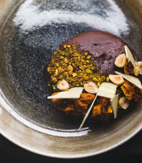 Gourmet chocolate dessert with pistachios, hazelnuts, and white chocolate on a rustic plate for a luxurious dining experience
