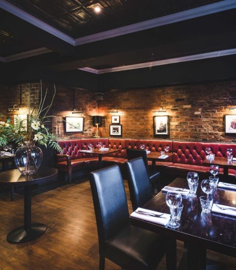 Cosy rustic restaurant interior with leather seating, brick walls, and elegant table settings for a fine dining experience