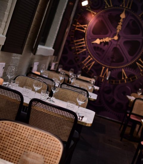 Elegant restaurant interior with neatly set tables and large decorative clock, creating a sophisticated dining ambiance