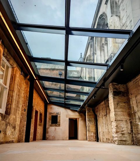 Historic stone hallway with glass roof showcasing architectural design and heritage elements, viewed from below.