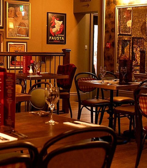 Cosy restaurant interior with warm lighting, elegantly set tables, vintage posters, and a welcoming atmosphere