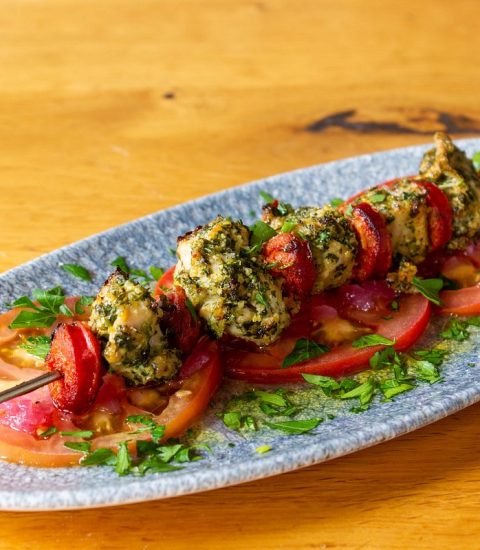 Herb-marinated chicken skewers with tomatoes and herbs on a plate, perfect for a healthy and flavourful meal