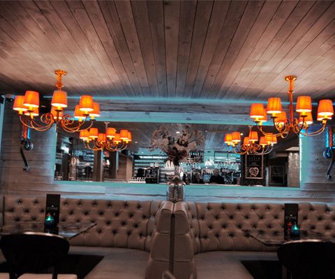 Cosy restaurant interior with elegant chandeliers and tufted seating, creating a warm and inviting dining atmosphere