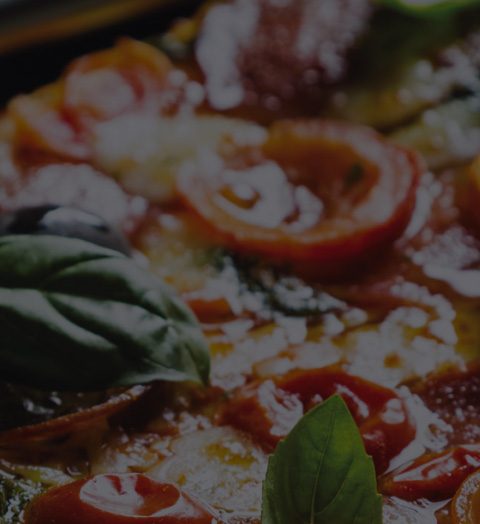 Close-up of a delicious gourmet pizza with fresh basil, olives, and melted cheese, ideal for Italian cuisine lovers