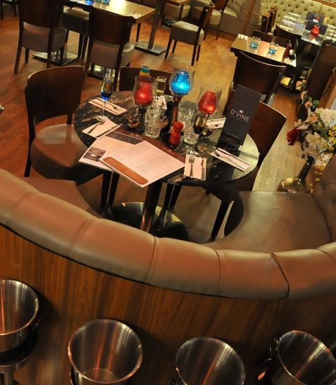 Luxury restaurant seating area with a round table, plush chairs, and elegant decor, set for dining on wooden flooring