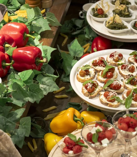 Fresh buffet display with vibrant red and yellow peppers, appetising canapés, leafy greens, and assorted salads