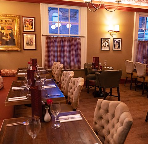 Cosy restaurant interior with elegant dining tables, vintage wall art, and warm lighting, creating a welcoming atmosphere