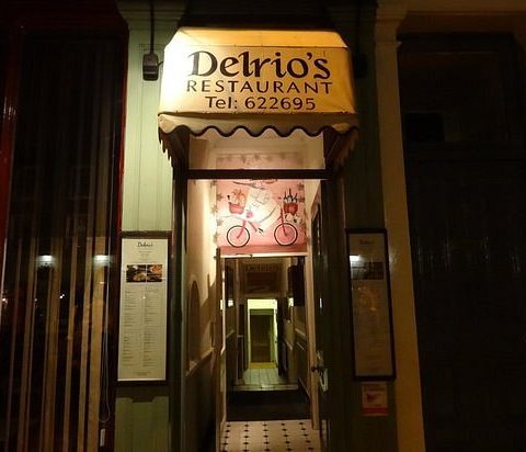 Entrance to Delrio's Restaurant with vintage decor and illuminated signage on a bustling street in the evening light