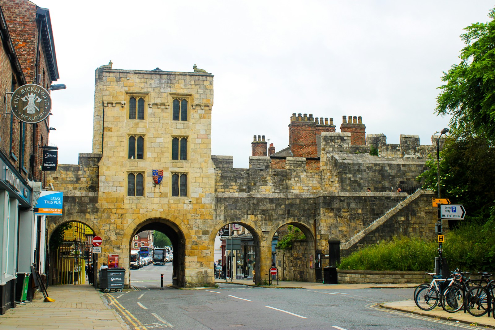 Historic stone gate in York city centre, England, with archways and surrounding brick buildings, bicycles parked nearby